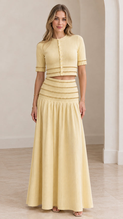 Model wearing butter yellow beaded crop top and pleated maxi skirt set front view