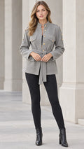 Full front view of model wearing grey textured belted utility jacket with black leggings and boots