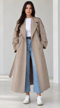 Front view of model wearing beige longline belted trench coat with jeans and white sneakers