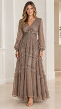 Front view of model wearing taupe plissé tiered maxi dress with long bishop sleeves and pearl brooch