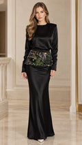 Front full-length view of woman wearing black long sleeve satin evening maxi gown with floral embroidered waist