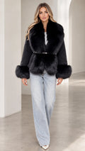 Front view of model wearing black belted jacket with plush faux fur collar and cuffs