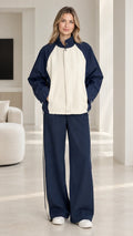 Front full-length view of woman wearing navy blue and cream colorblock tracksuit set