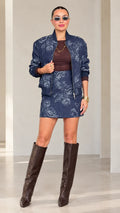Front full-length view of model wearing Navy Blue paisley jacquard bomber jacket and skirt set with tall boots