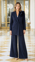 Front view of a woman wearing a navy floral brooch blazer and wide-leg pants suit