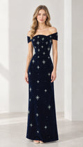 Front view of woman wearing navy blue off-the-shoulder velvet maxi dress with beaded starburst details