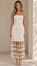 Front view of model wearing cream strapless lace midi dress with beaded tassel hem
