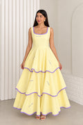 Model wearing pastel yellow sleeveless tiered maxi dress with purple contrast trim, front view