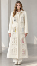 Full-length front view of model wearing ivory architectural window appliqué maxi coat