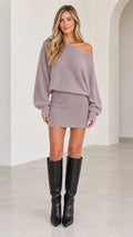 Front view of woman wearing mauve one-shoulder knit mini sweater dress with black knee-high boots