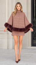 Front view of model wearing a dusty rose plaid cape coat with plush faux fur trim and matching skirt