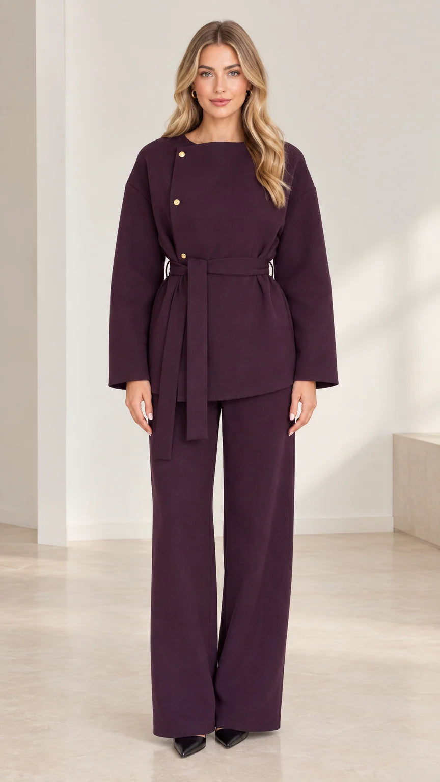 Front full-length view of woman wearing deep plum asymmetrical belted top and wide-leg pant set