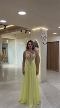 Front view of model wearing a light yellow halter embellished evening gown