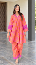 Front full view of woman wearing coral floral print flared tunic and pants set with lace trim