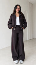 Front view of model wearing dark brown zip track jacket and matching wide leg pants set