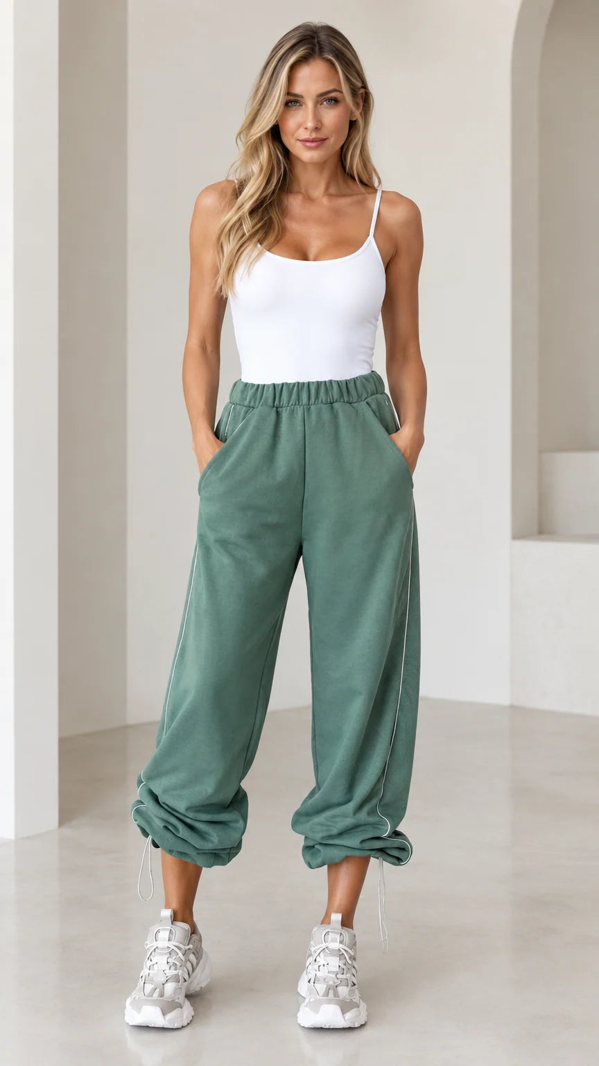 Front view of model wearing sage green relaxed cinch-bottom joggers with white tank top and sneakers