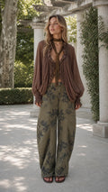 Model wearing olive green floral wide-leg pants and brown boho ruffle blouse front view