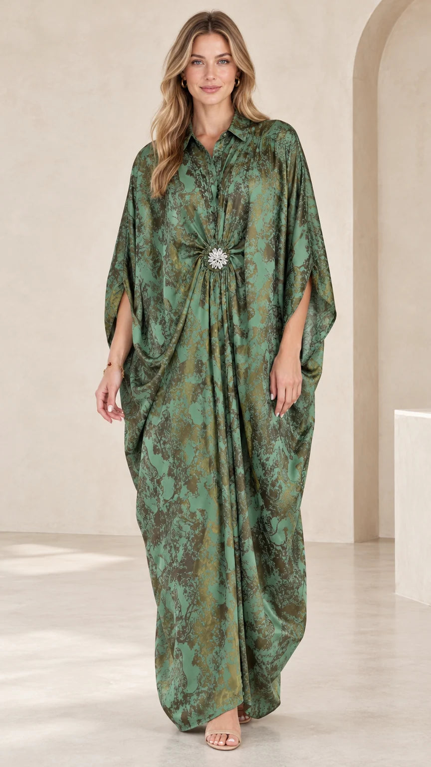 Front full view of woman wearing emerald green printed kaftan maxi dress with crystal brooch