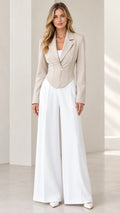Model wearing a beige corset blazer with front zip and white wide-leg trousers