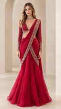 Front view of woman wearing crimson red pre-draped lehenga saree with embroidered border and long-sleeve blouse
