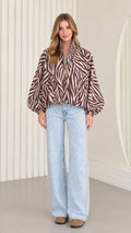 Front view of model wearing mocha brown zebra print balloon sleeve zip-up jacket with light-wash wide-leg jeans