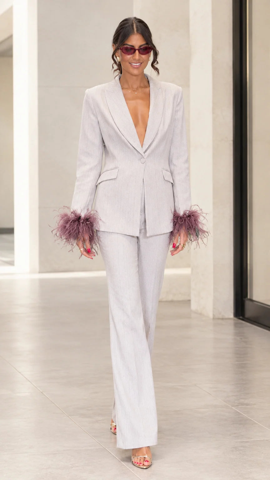 Front full-length view of woman wearing light grey tailored suit with mauve feather cuffs and flare pants