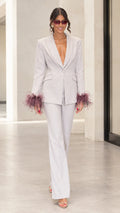 Front full-length view of woman wearing light grey tailored suit with mauve feather cuffs and flare pants