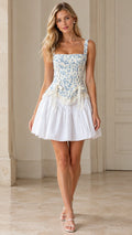 Front view of model wearing blue floral corset drop-waist mini dress with white flared skirt