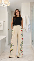 Front view of model wearing cream floral embroidered high-waist wide-leg trousers with black sleeveless top