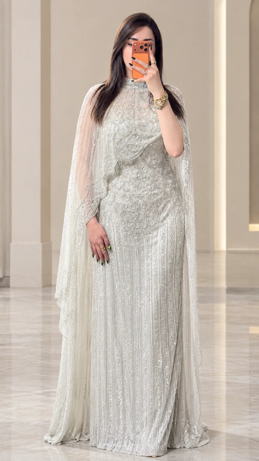 Front view of woman wearing silver beaded cape evening gown with high neckline