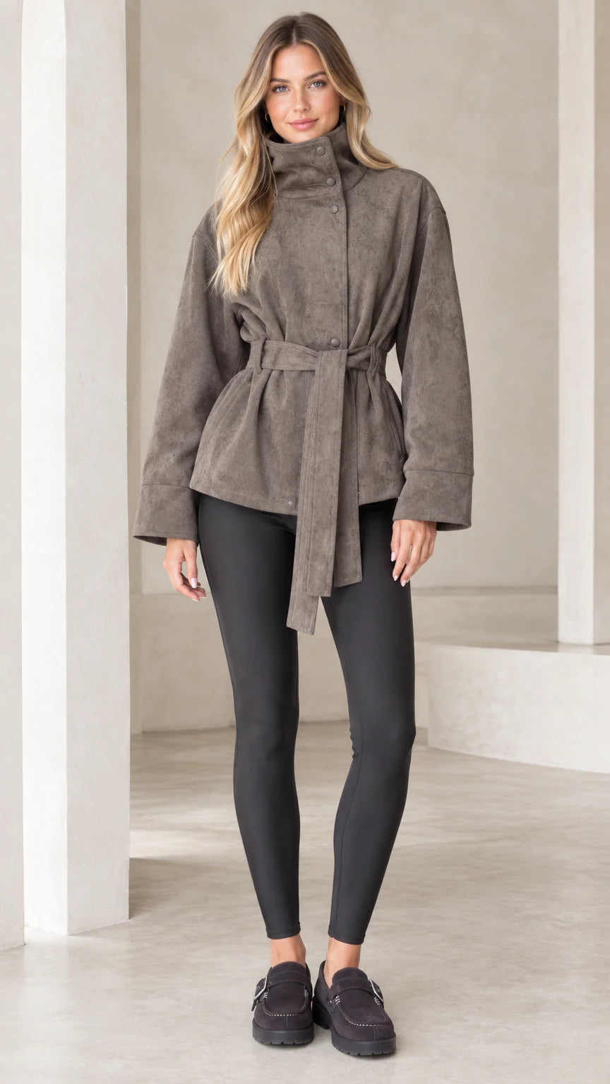 Front view of model wearing taupe high-neck belted faux suede jacket with black leggings