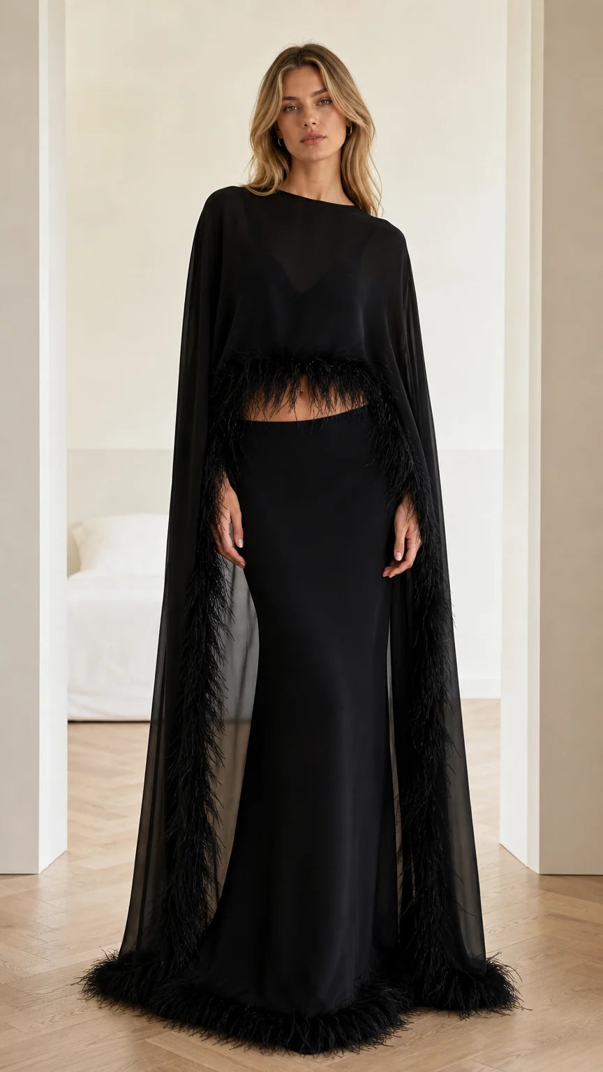 Front view of black two-piece evening gown with feather-trimmed cape top and maxi skirt