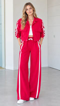 Front full view of woman wearing red 2-piece side stripe cropped jacket and wide-leg track pants set