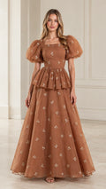 Front full view of woman wearing toffee brown floral embroidered puff sleeve peplum maxi gown