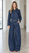 Full front view of model wearing dark blue asymmetrical denim jacket and wide leg pants set