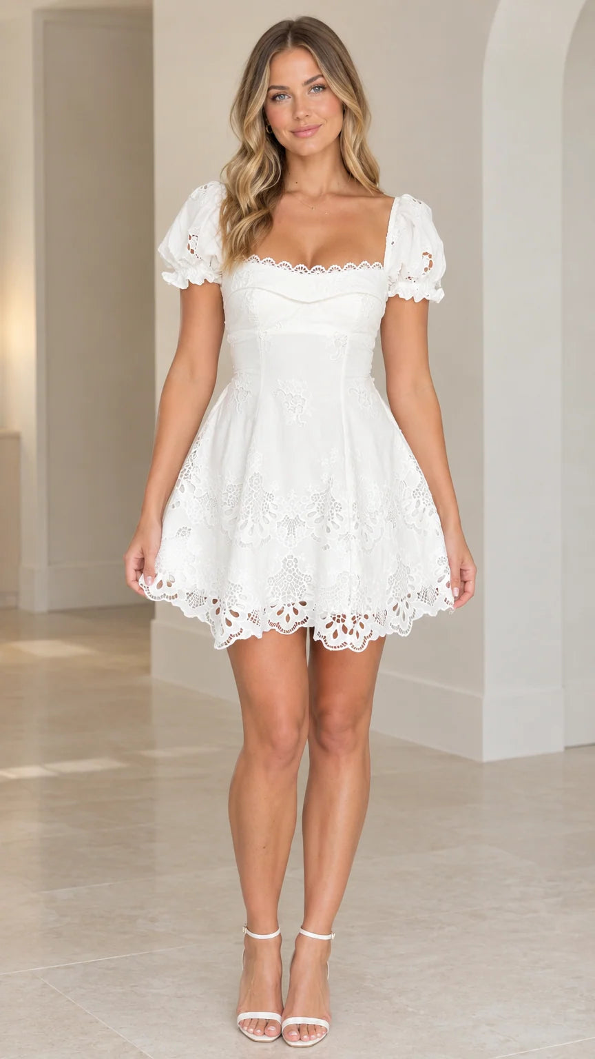 Front view of model wearing white sweetheart puff sleeve eyelet mini dress with strappy heels