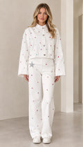 Front full view of woman wearing white rhinestone embellished cropped jacket and matching wide-leg pants