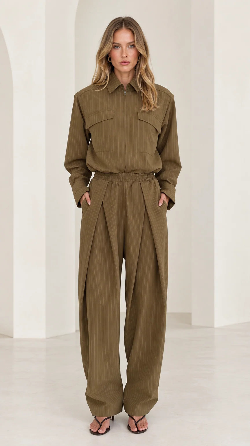 Front full-length view of woman wearing olive green long sleeve pleated wide-leg utility jumpsuit