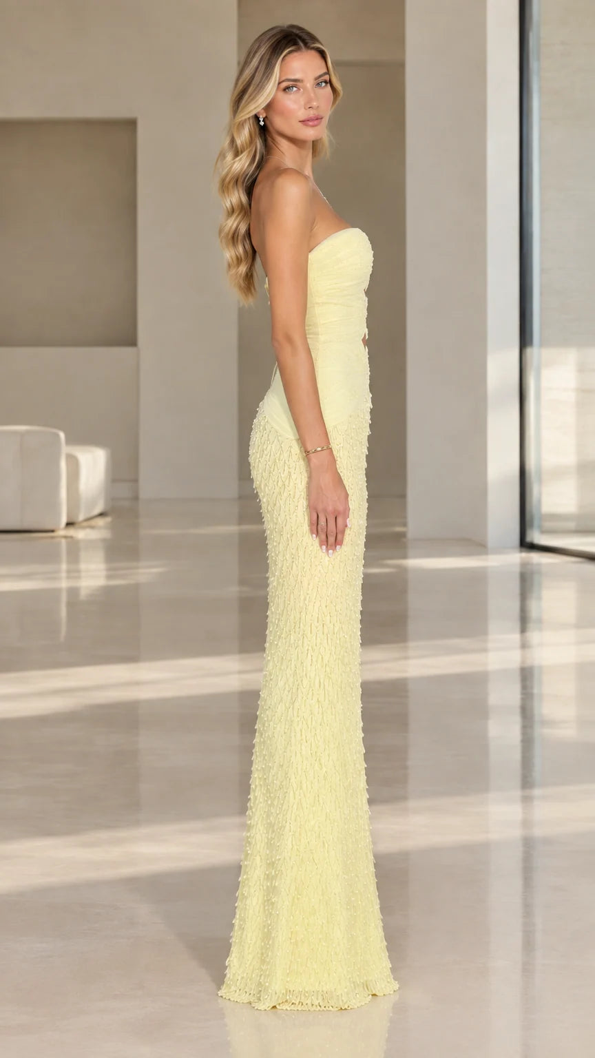 Side view of model wearing pale yellow strapless cutout floor-length evening dress