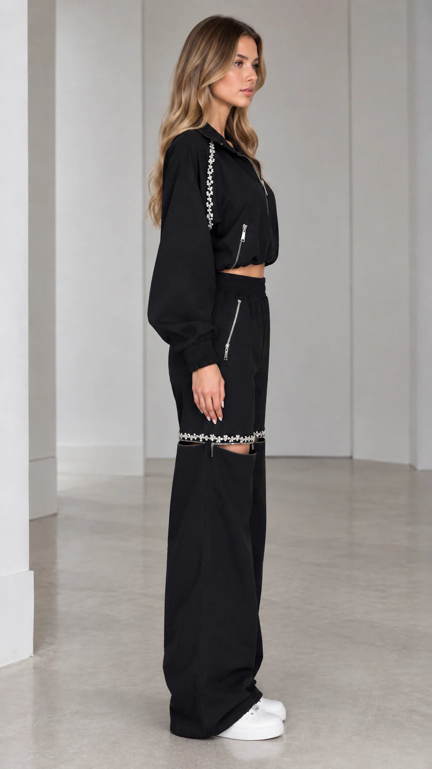 Side profile of model wearing black two-piece cropped jacket and wide-leg tracksuit set