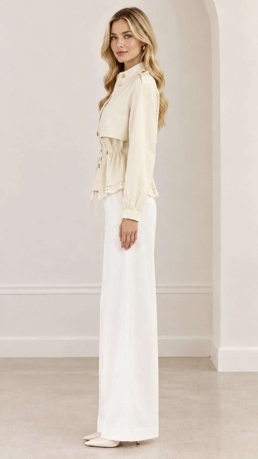 Side profile view of woman wearing cream drawstring peplum jacket with lace trim
