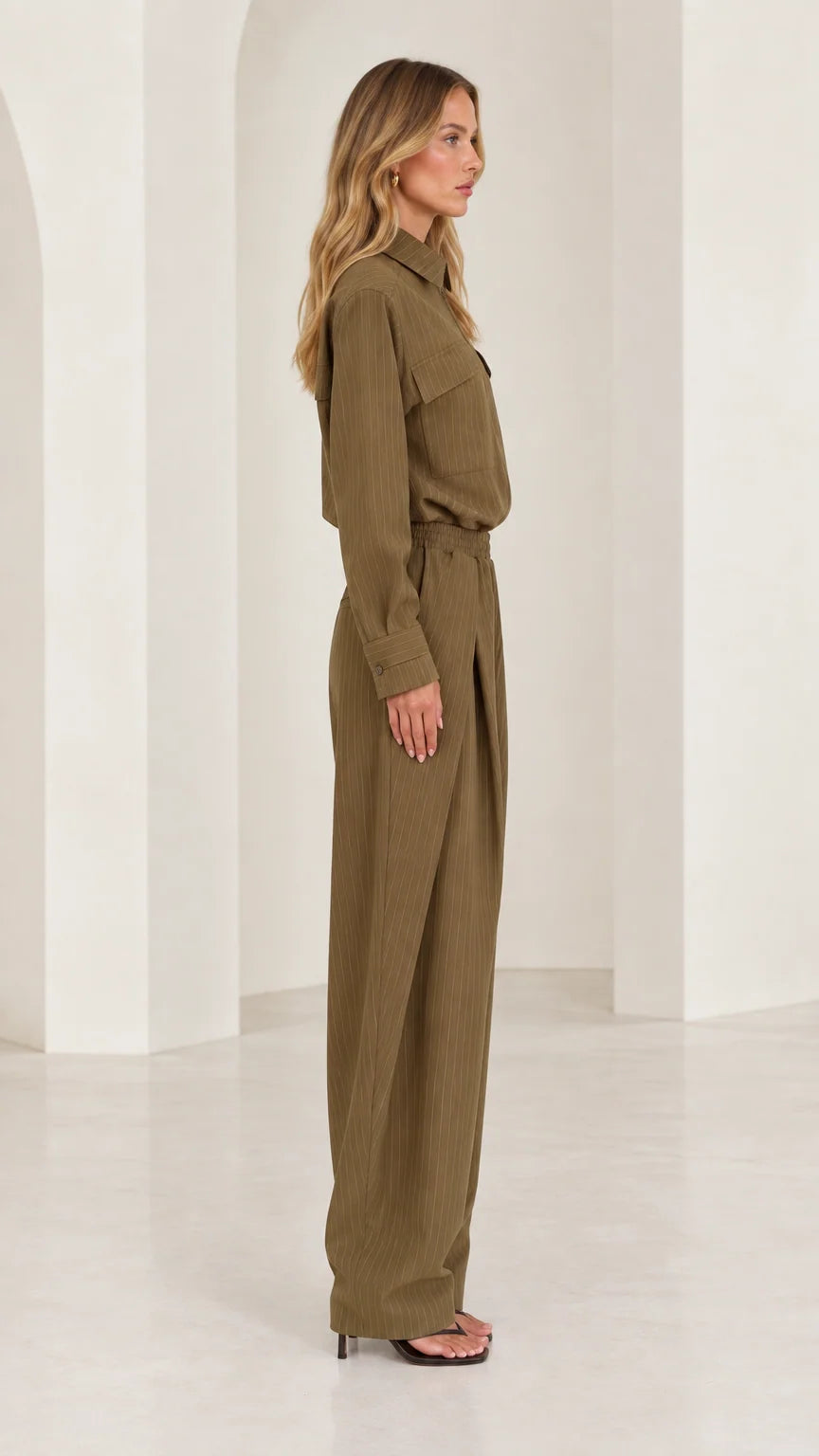 Side full-length view of woman wearing olive green tailored wide-leg jumpsuit