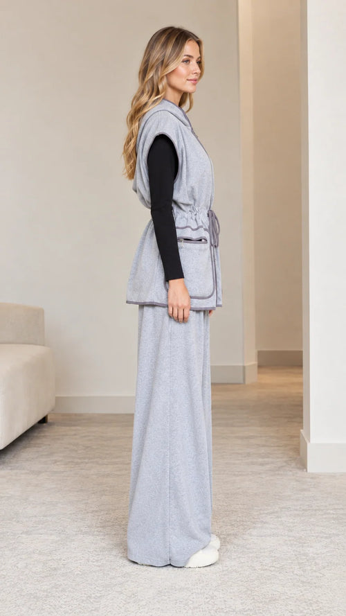 Side profile view of model in heather grey drawstring hooded vest and relaxed trousers