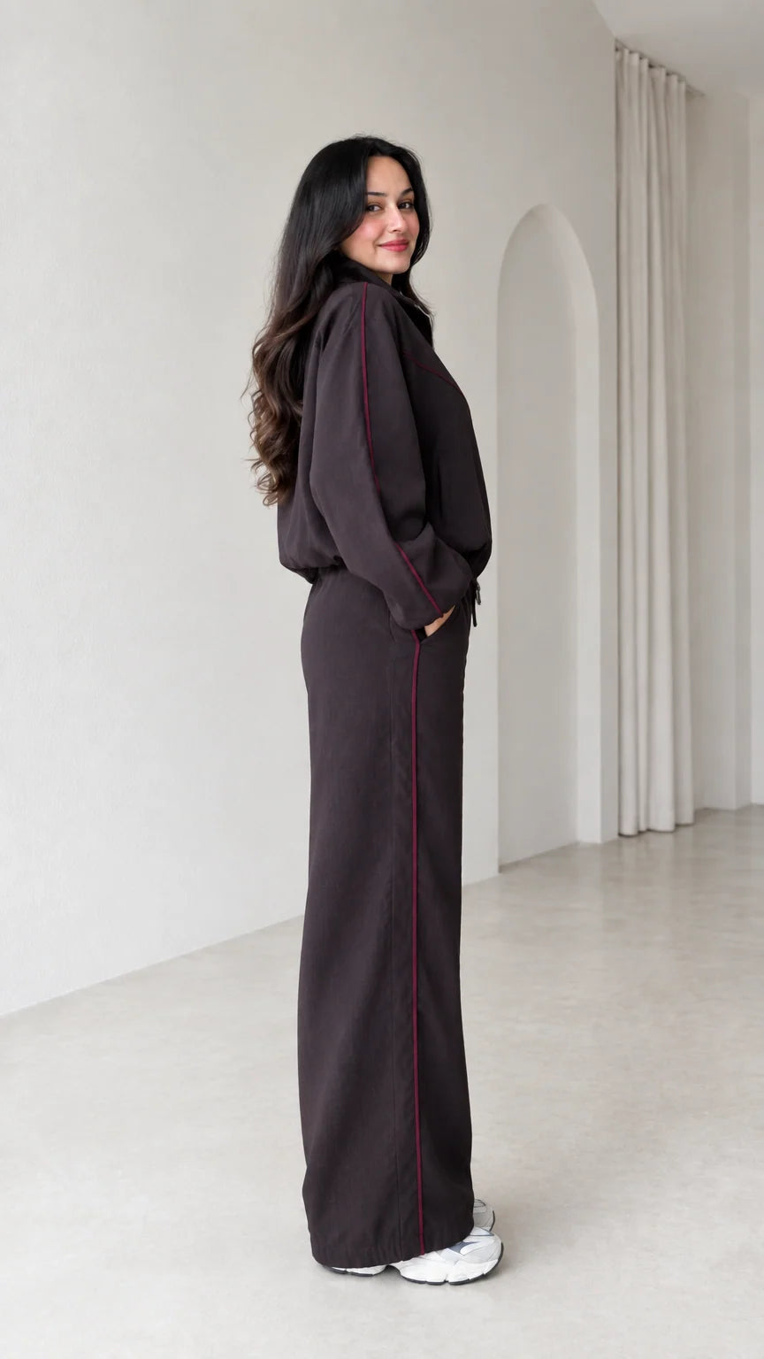 Side profile of model wearing dark brown two-piece tracksuit set with contrast piping