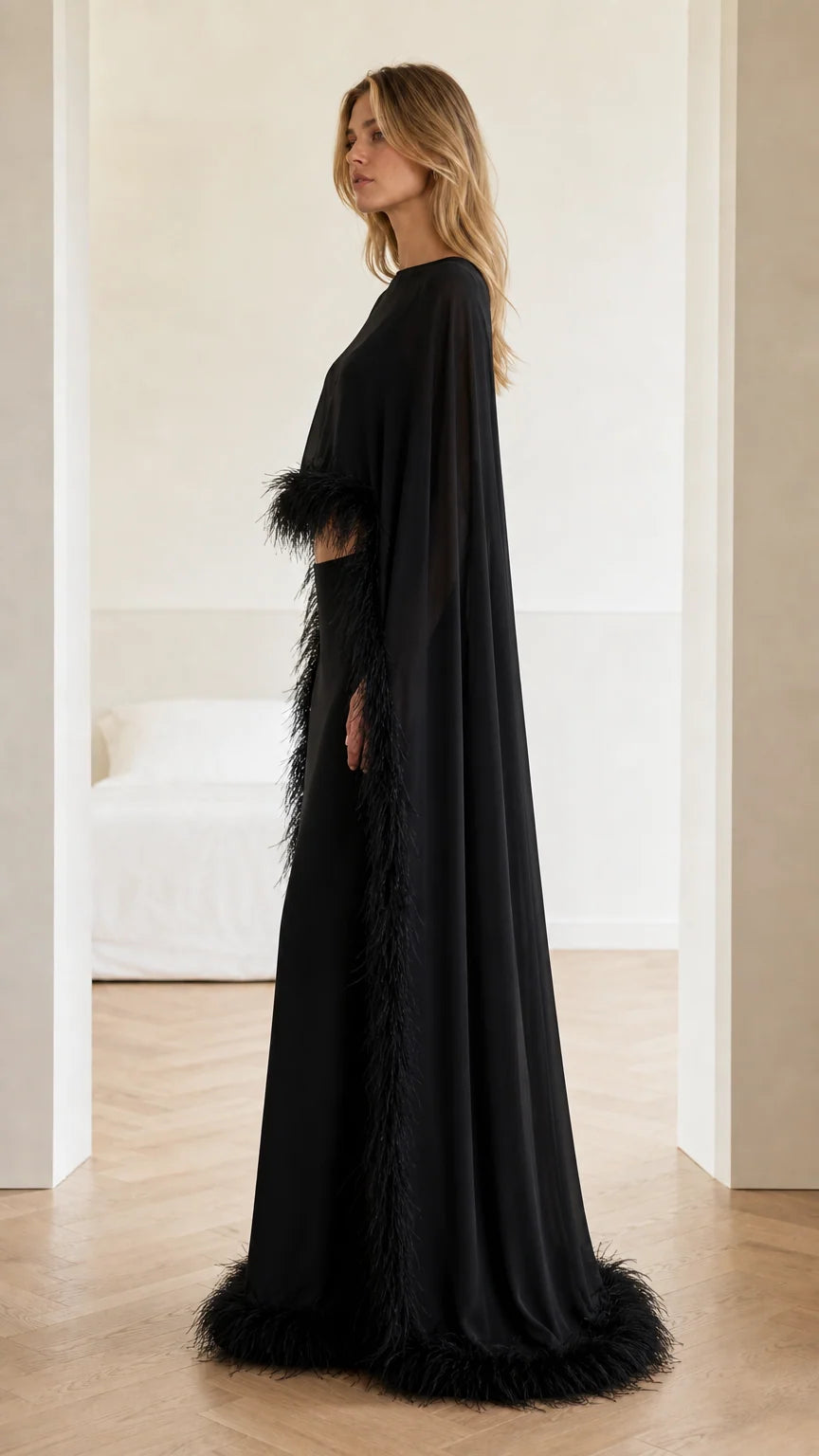 Side profile view of woman wearing black formal cape gown with feather detail
