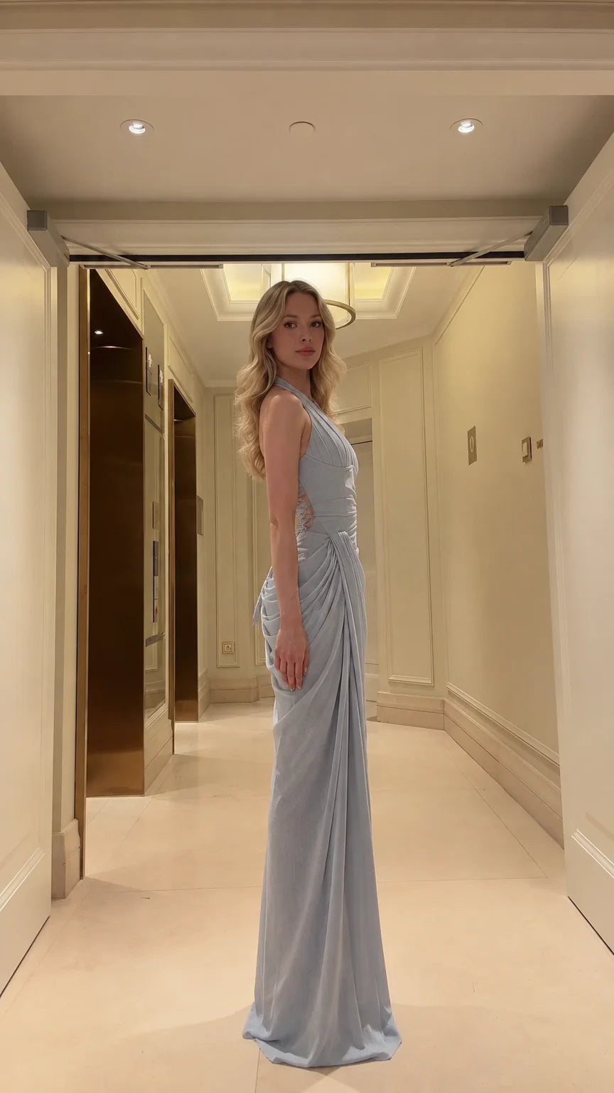 Side profile view of model wearing light blue draped halter evening gown