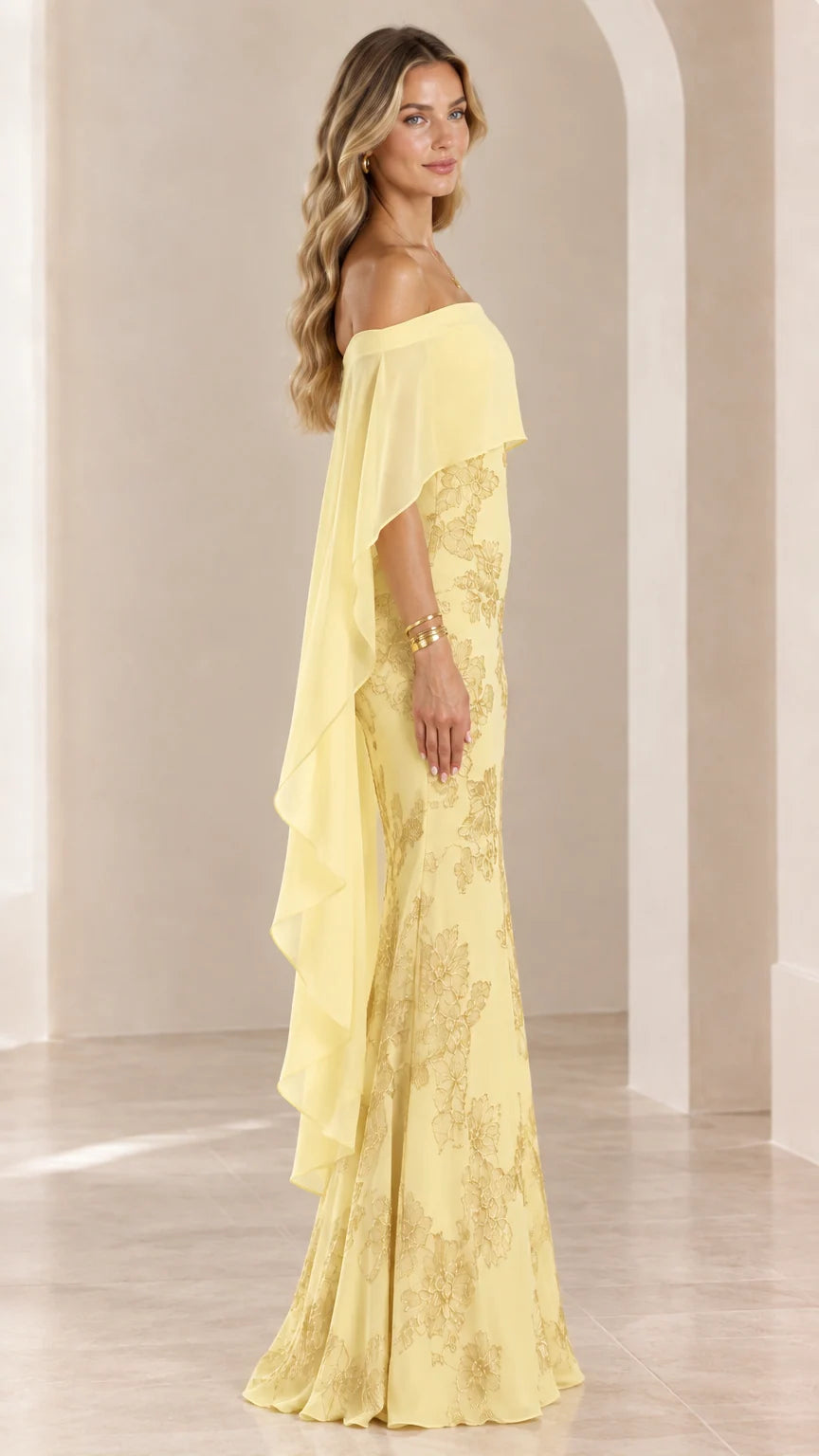 Side profile of woman wearing yellow floor-length formal dress with sheer cape overlay