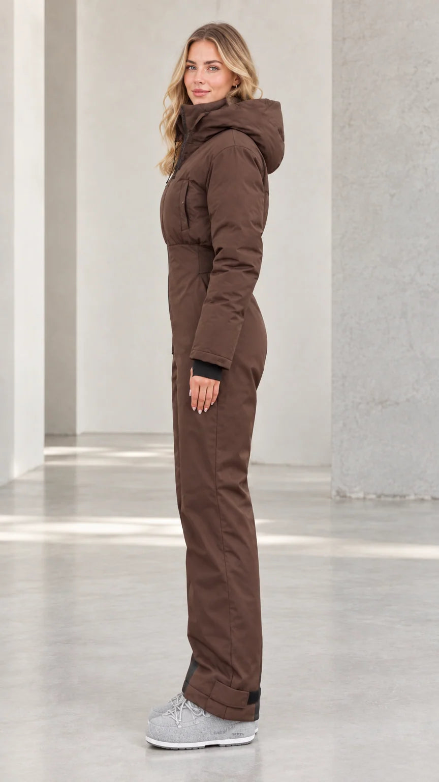 Side profile of woman in brown fitted thermal snow jumpsuit