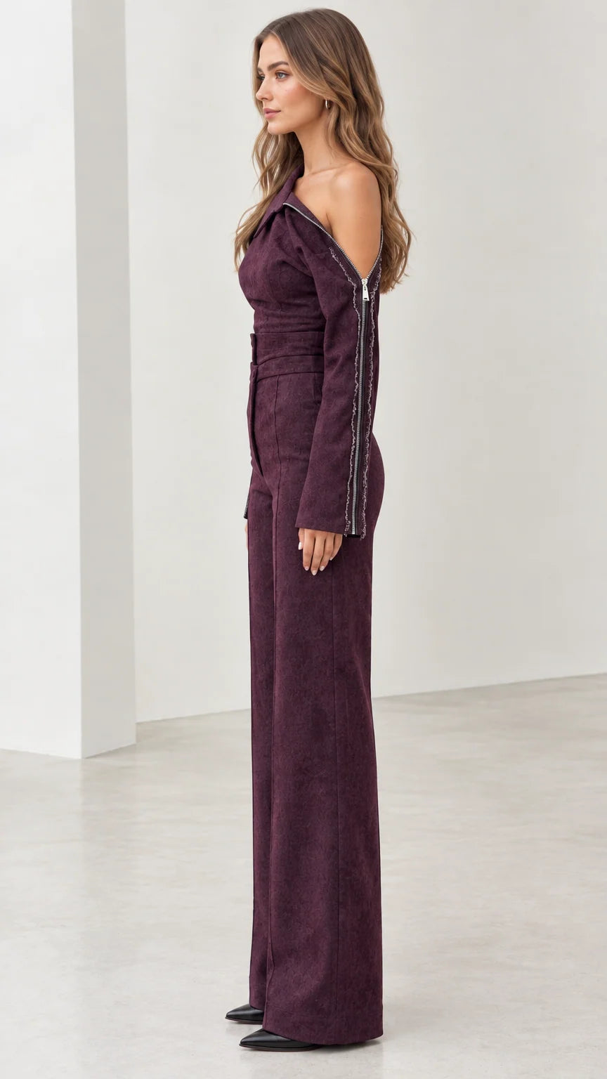 Side profile of model in tailored plum wide-leg jumpsuit with zipper detailing
