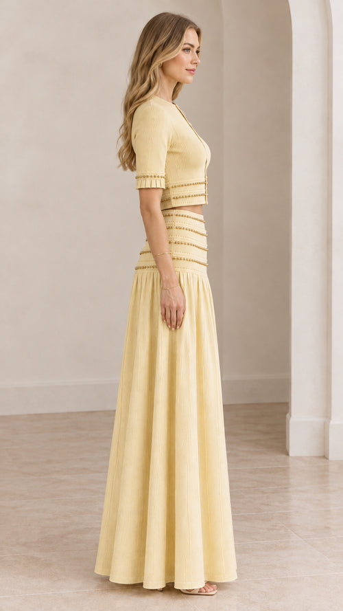 Side profile of model wearing butter yellow two-piece crop top and maxi skirt set